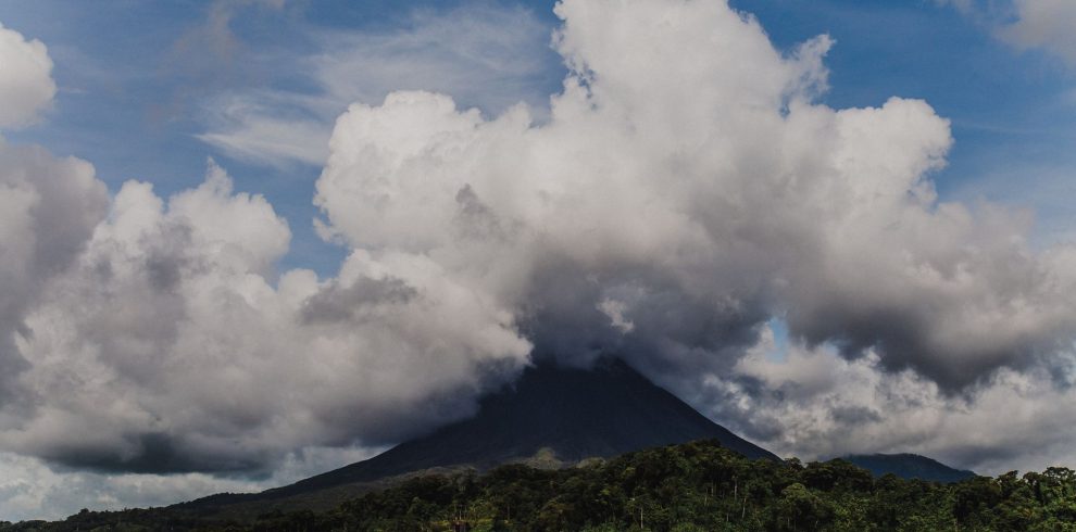 A stunning landscape of Arenal Volcano with clouds and a serene lake view, capturing nature's beauty.