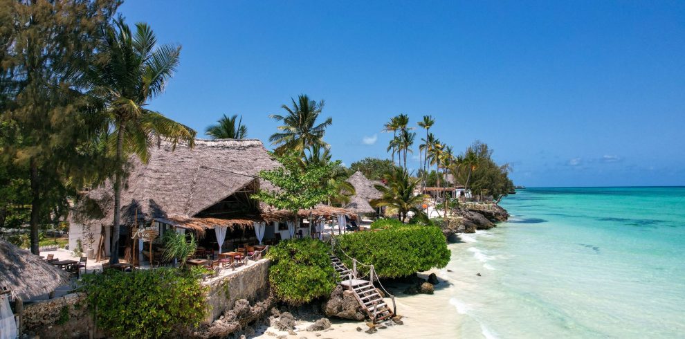 Beautiful tropical beach resort in Zanzibar, Tanzania, with thatched huts, palm trees, and turquoise waters.