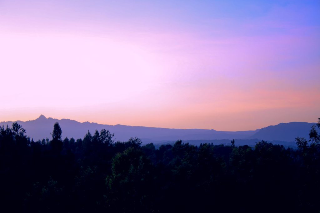 Scenic view of sunset over Mount Kenya in Meru County, Kenya. Vibrant colors and silhouette of trees create a captivating landscape.