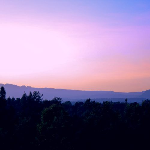 Scenic view of sunset over Mount Kenya in Meru County, Kenya. Vibrant colors and silhouette of trees create a captivating landscape.