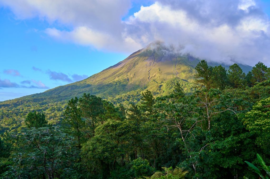 Breathtaking view of a lush green landscape with a majestic volcanic mountain under a cloudy sky.