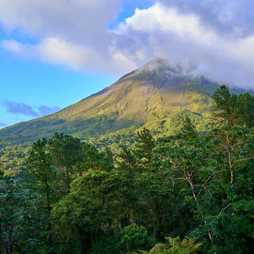 Breathtaking view of a lush green landscape with a majestic volcanic mountain under a cloudy sky.