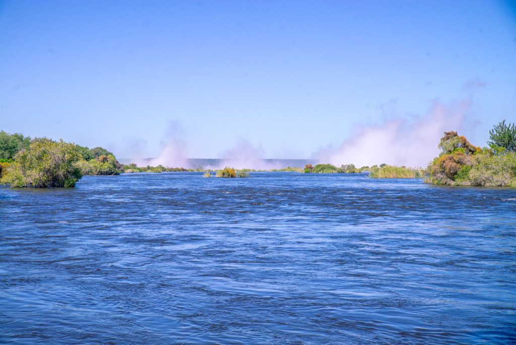 Beautiful river scene with mist, vibrant greenery, and clear blue sky.