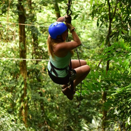 A woman ziplining through lush Costa Rican forests, showcasing adventure and nature.